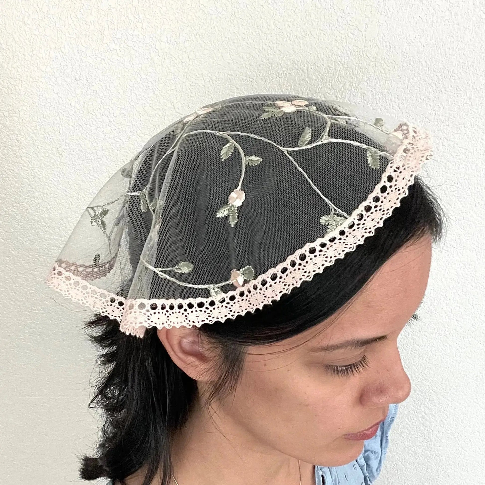 Girl wearing a light pink floral lace cap chapel veil for Catholic mass.