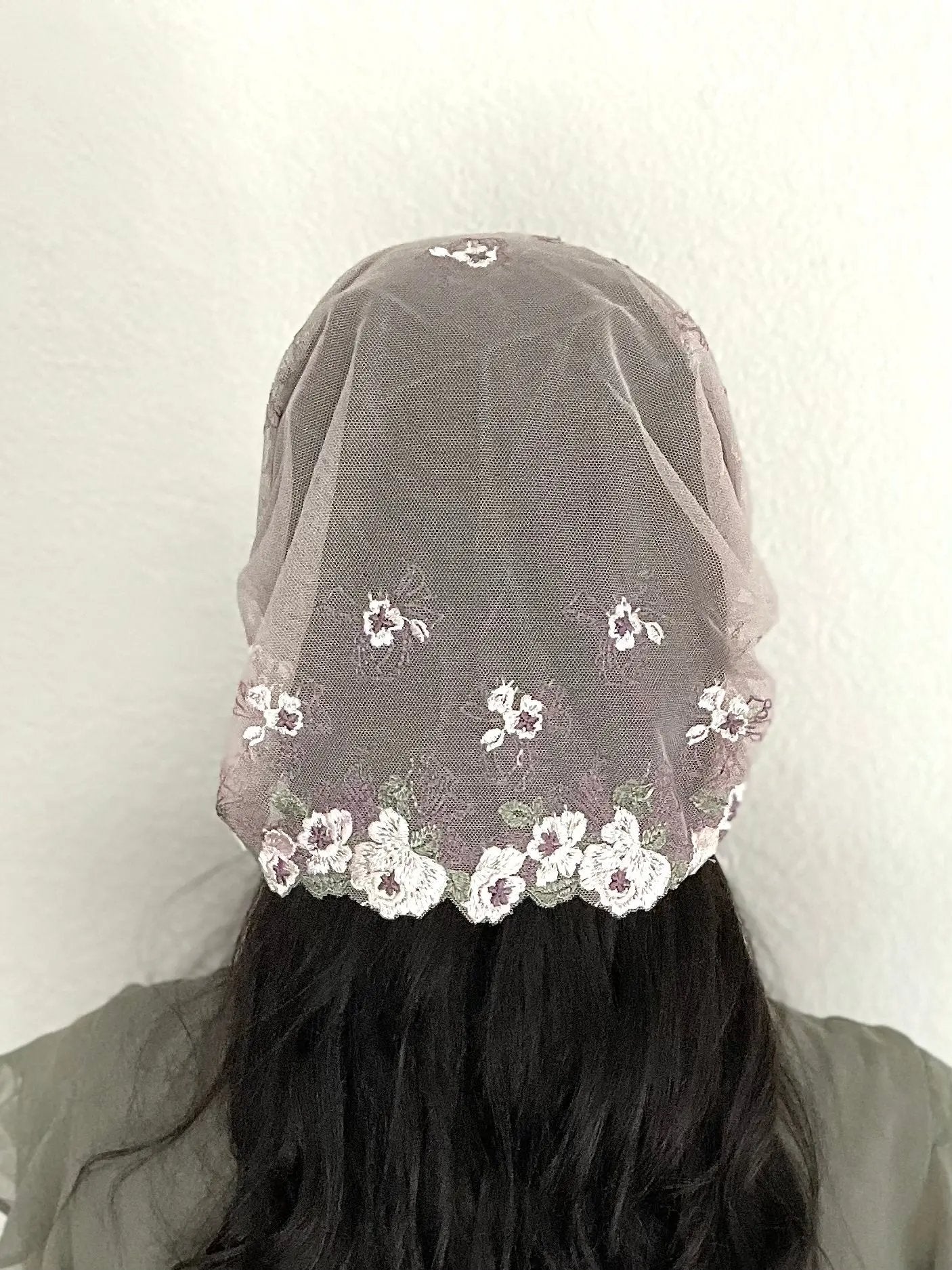 Back view of girl wearing a purple lace embroidered traditional Christian mass veil headscarf.