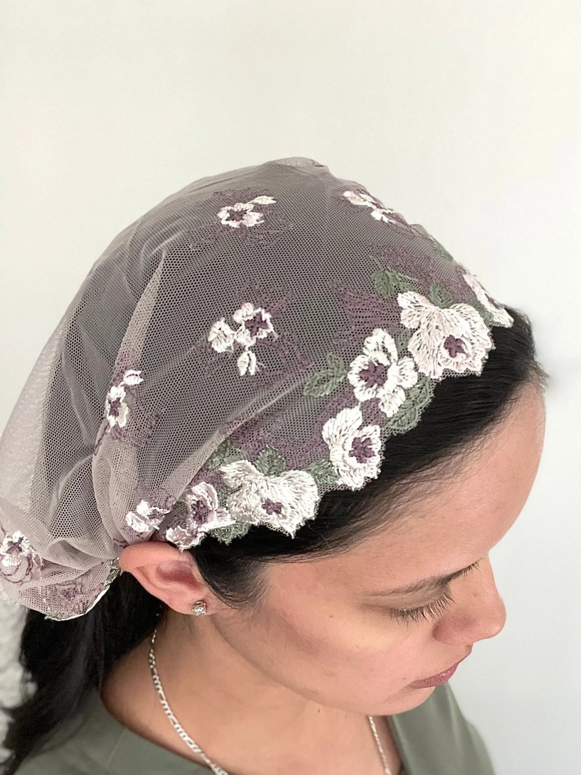 Woman wearing a soft purple lace embroidered traditional Catholic mass veil headscarf.
