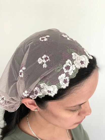 Woman wearing a soft purple lace embroidered traditional Catholic mass veil headscarf.