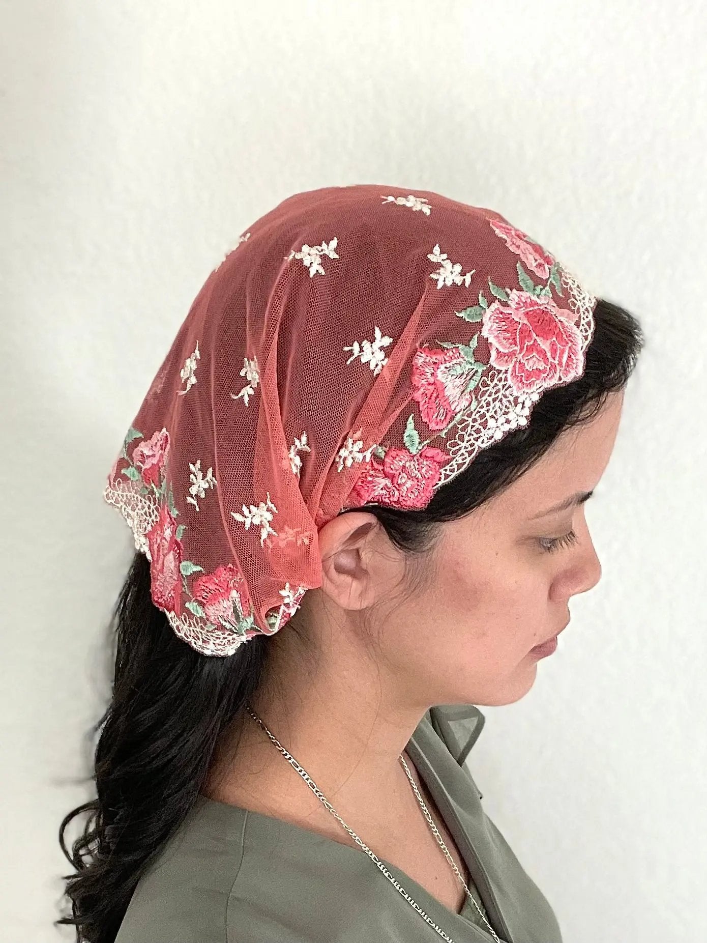 Girl wearing a small beautiful red and pink embroidered lace chapel veil kerchief.