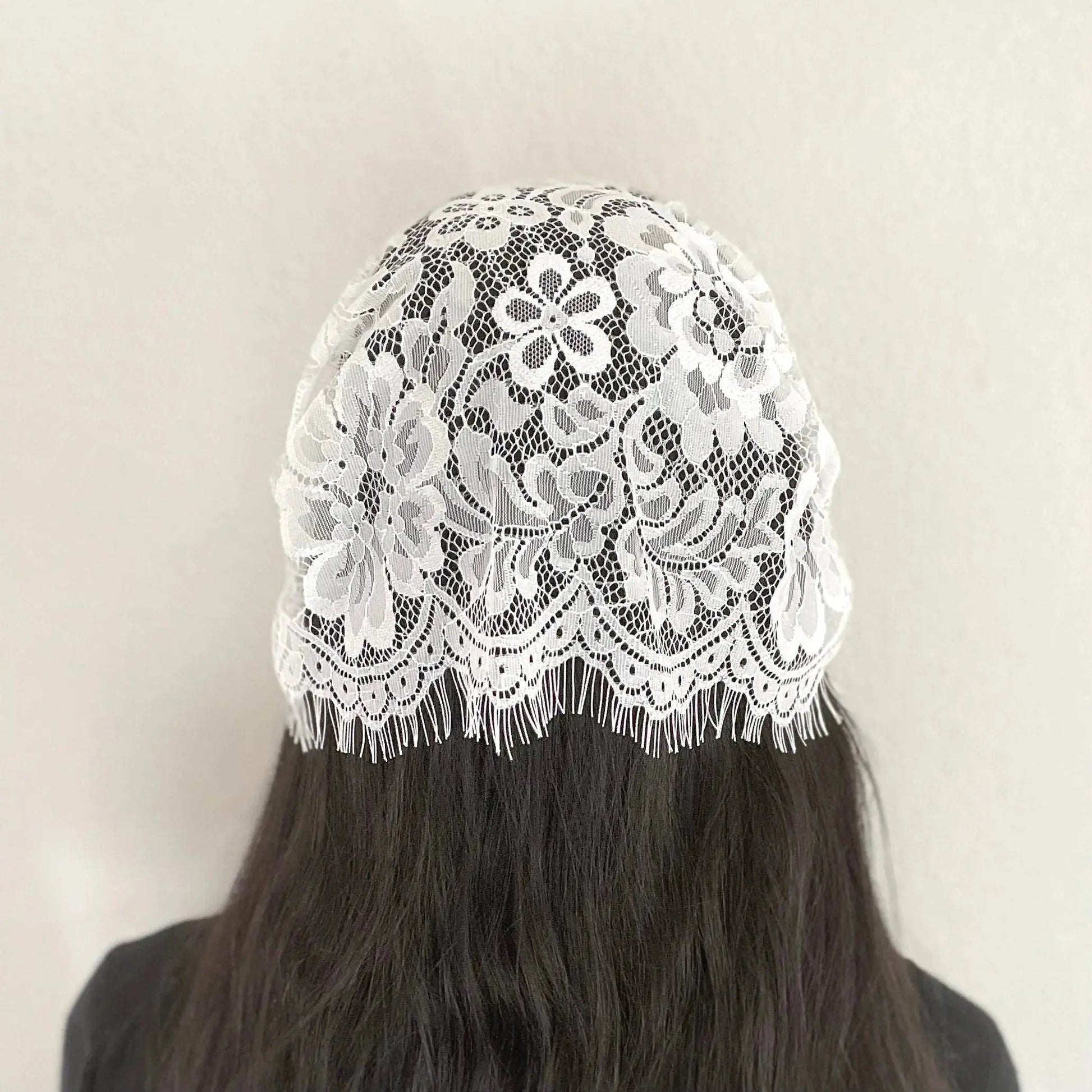 Back of girl wearing a traditional white eyelash lace Catholic chapel veil kerchief.