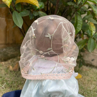 Baby wearing little pink lace veil with floral embroidery. The mantilla is perfect for Traditional Catholic Christian Mass