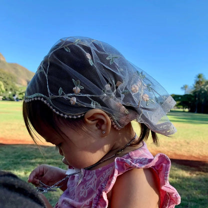 Toddler wearing pale pink lace veil with floral embroidery. The mantilla is perfect for Traditional Catholic Christian Mass