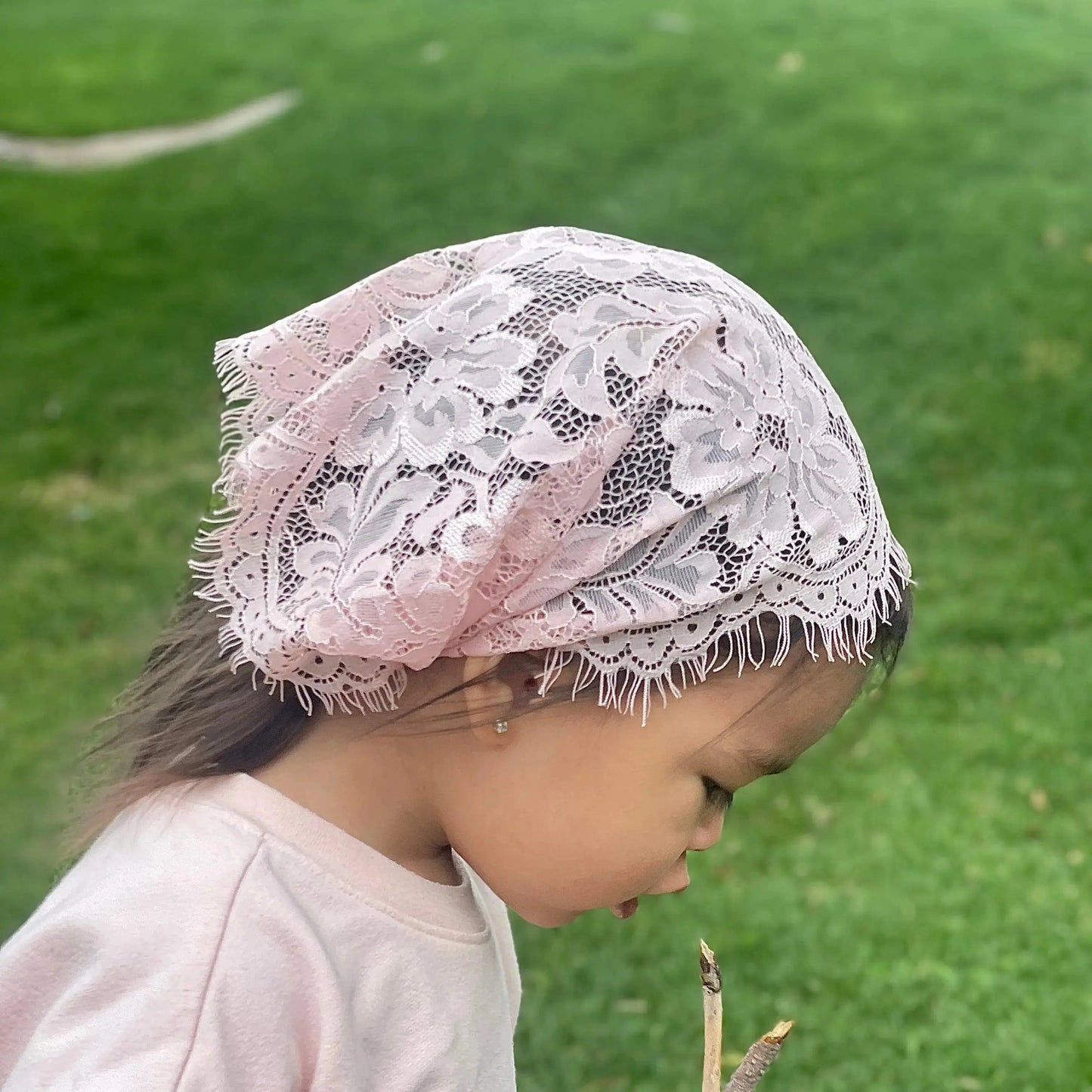 Baby wearing a soft pink eyelash lace veil for Traditional Catholic Mass.