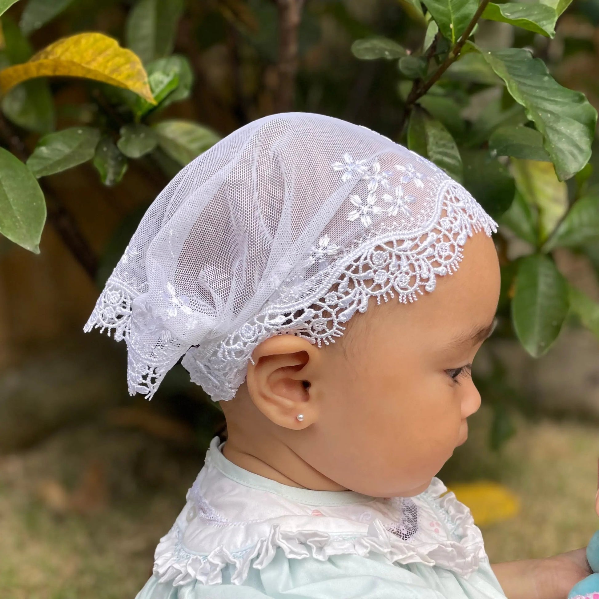 Infant in a ivory white embroidered lace catholic chapel veil for baptism.