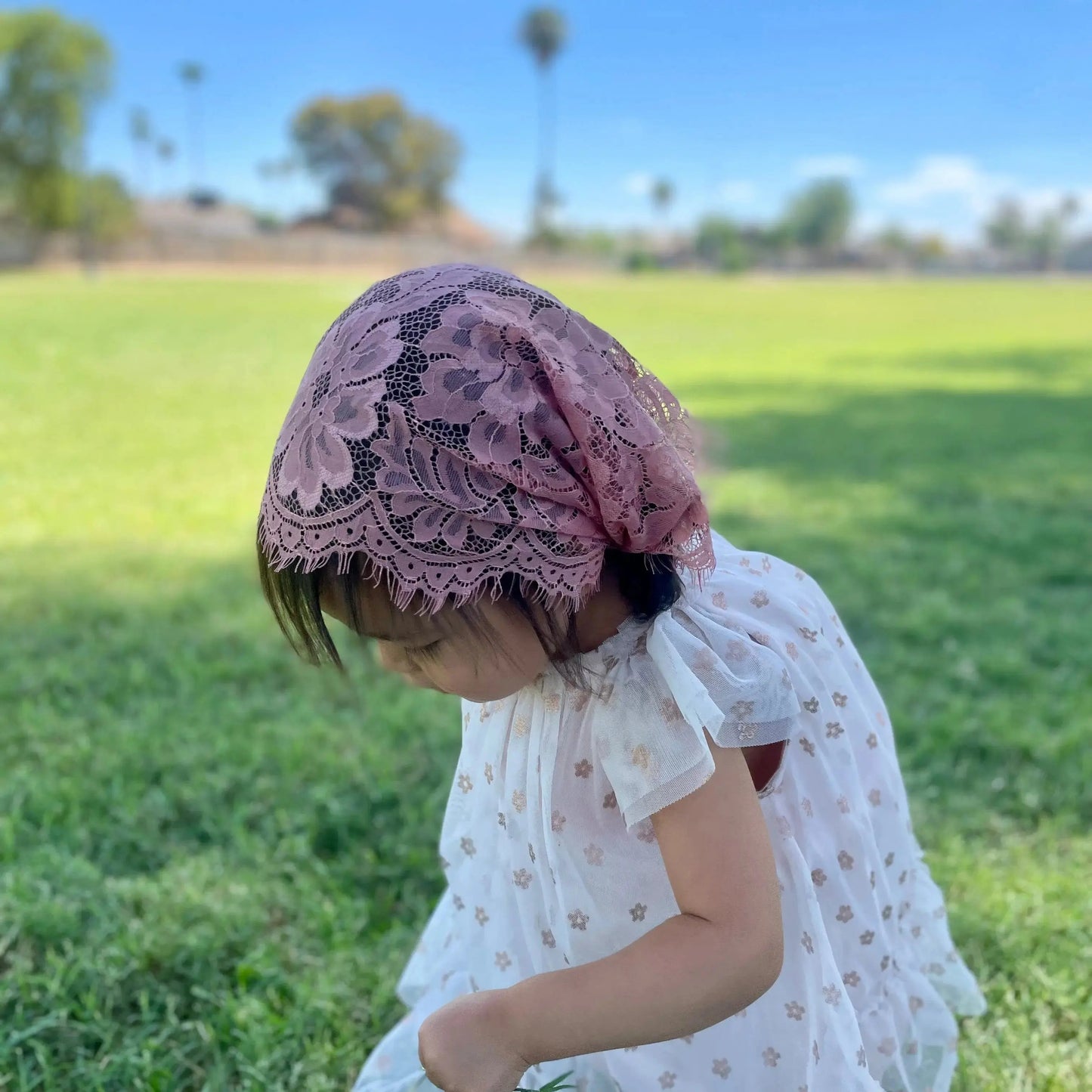 Infant in a dark pink floral eyelash lace catholic chapel veil for Catholic Mass.