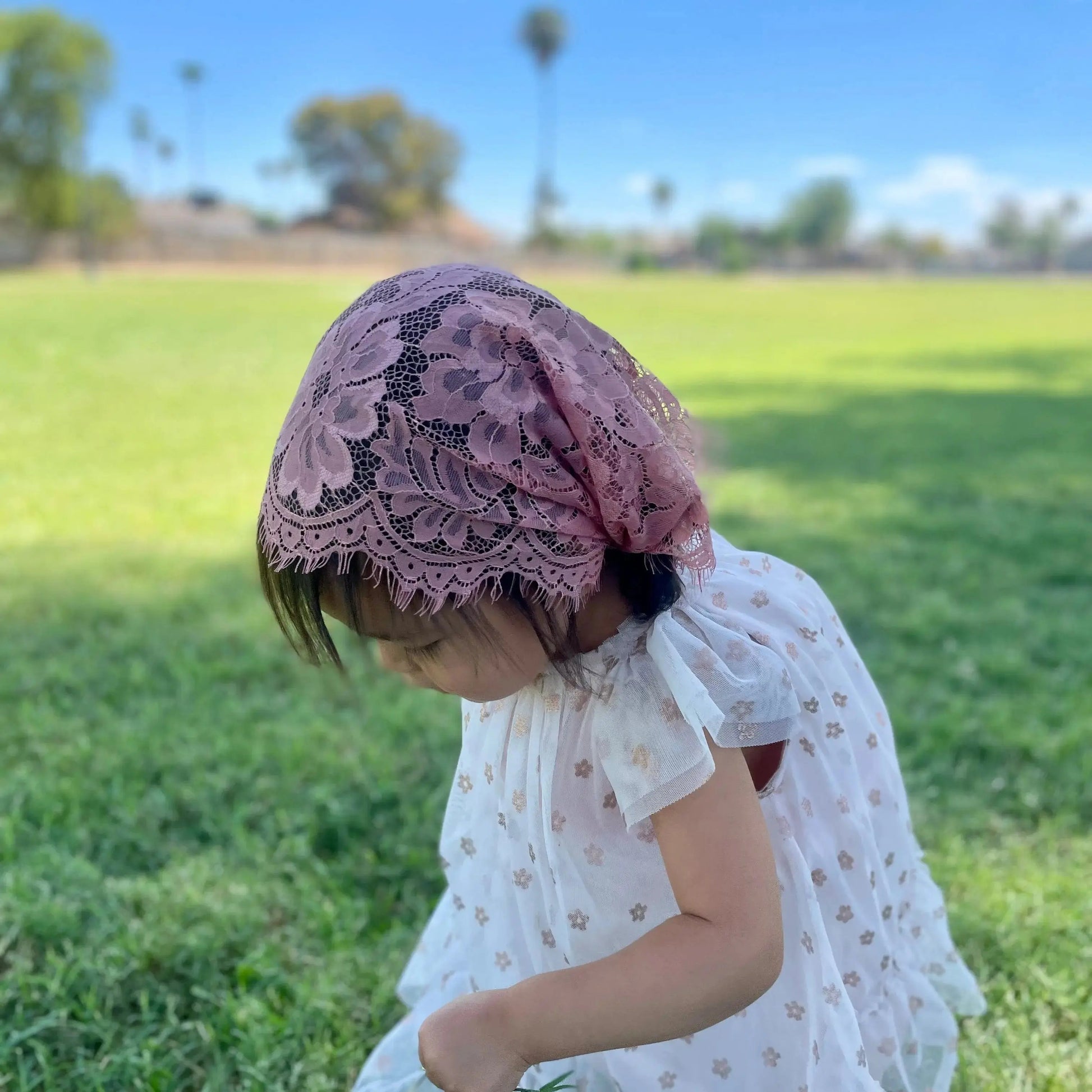 Infant in a dark pink floral eyelash lace catholic chapel veil for Catholic Mass.