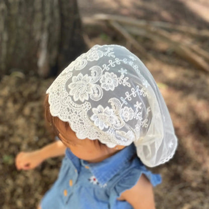 The top view of a baby wearing a chapel veil with embroidery detailing. 
