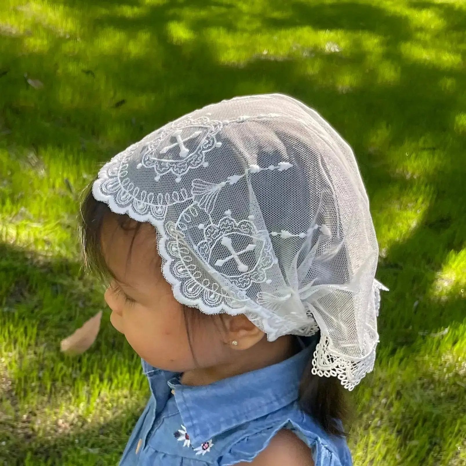 Infant wearing an ivory embroidered lace chapel veil for Catholic baptism. 
