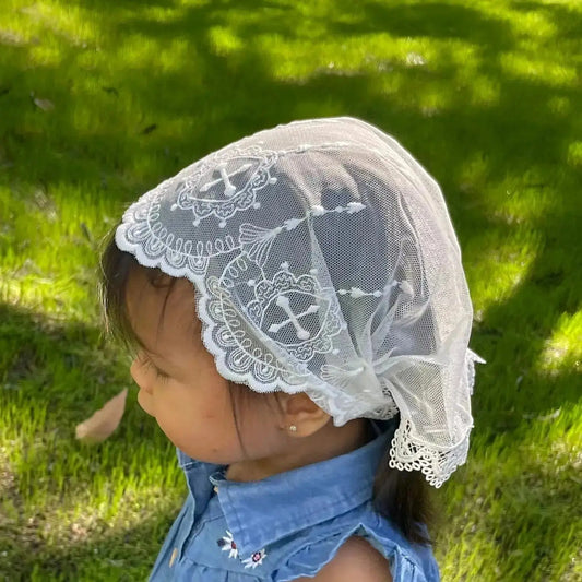 Infant wearing an ivory embroidered lace chapel veil for Catholic baptism. 