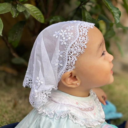 Baby wearing a soft white embroidered lace chapel veil, perfect for a Christian baptism.