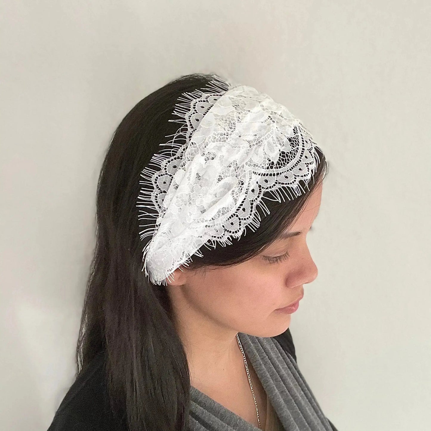 Girl wearing a white kerchief lace veil in a scrunched headband style.