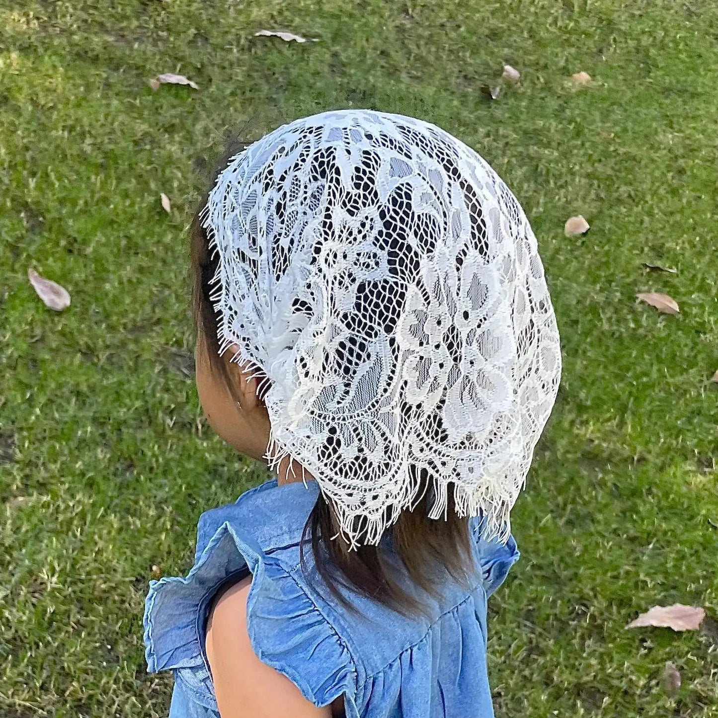 Back view of a toddler wearing a simple white eyelash lace baptism veil.