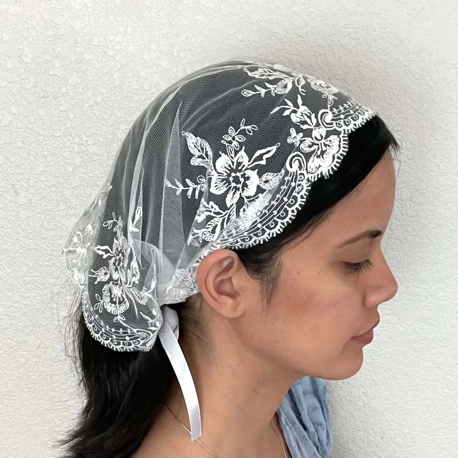 Girl wearing a beautiful small white embroidered lace chapel veil kerchief. 