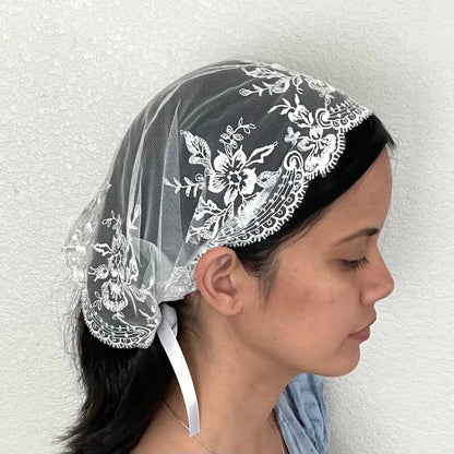 Girl wearing a beautiful small white embroidered lace chapel veil kerchief. 